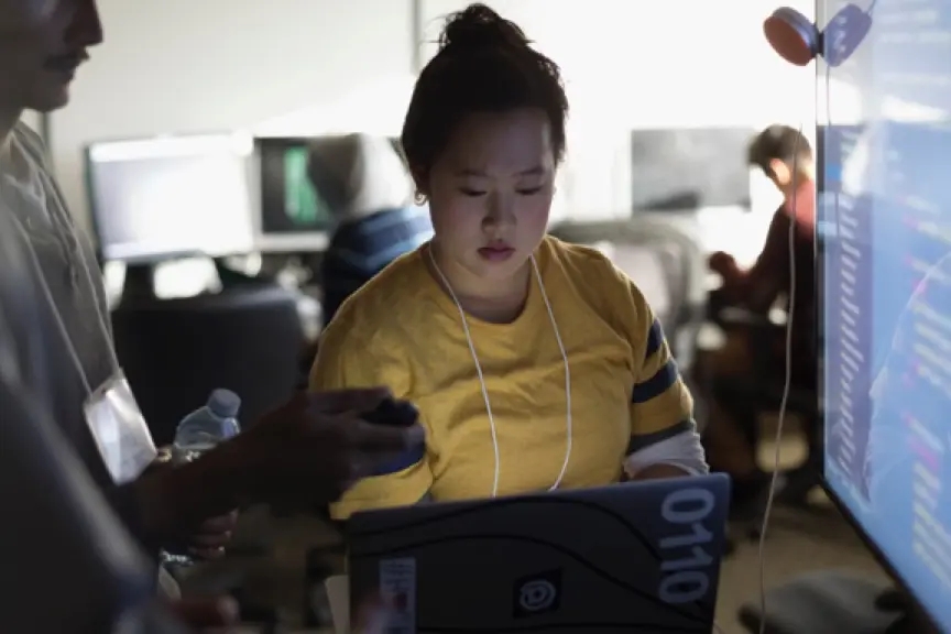 Femme travaillant avec un collègue devant un ordinateur portable.